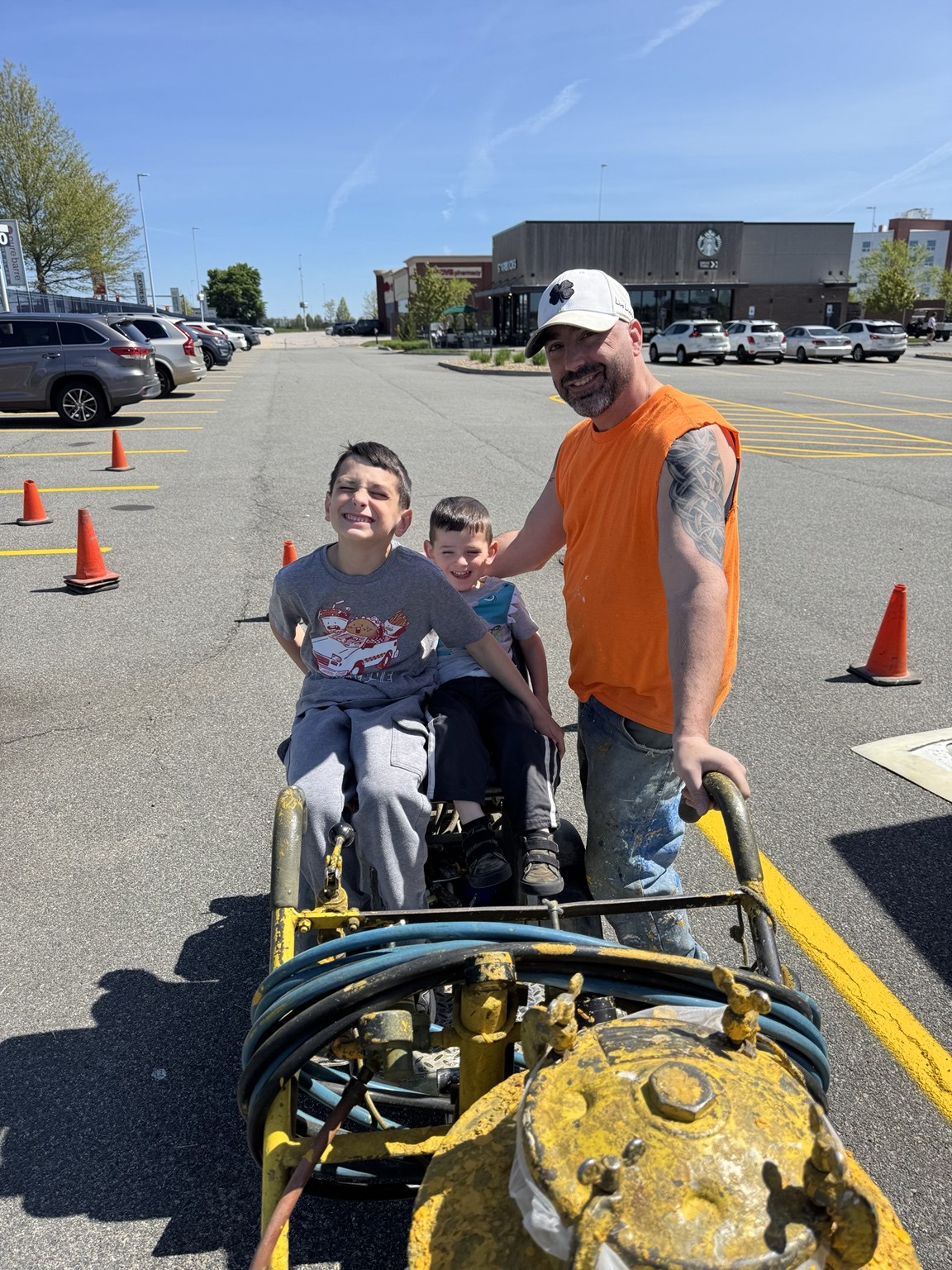 Kevin with his children beside line striping equipment